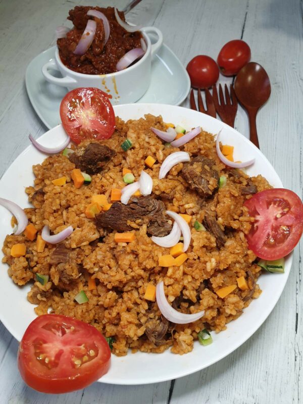 Ghanaischer Jollof-Reis mit Lammfleisch, garniert mit Zwiebeln